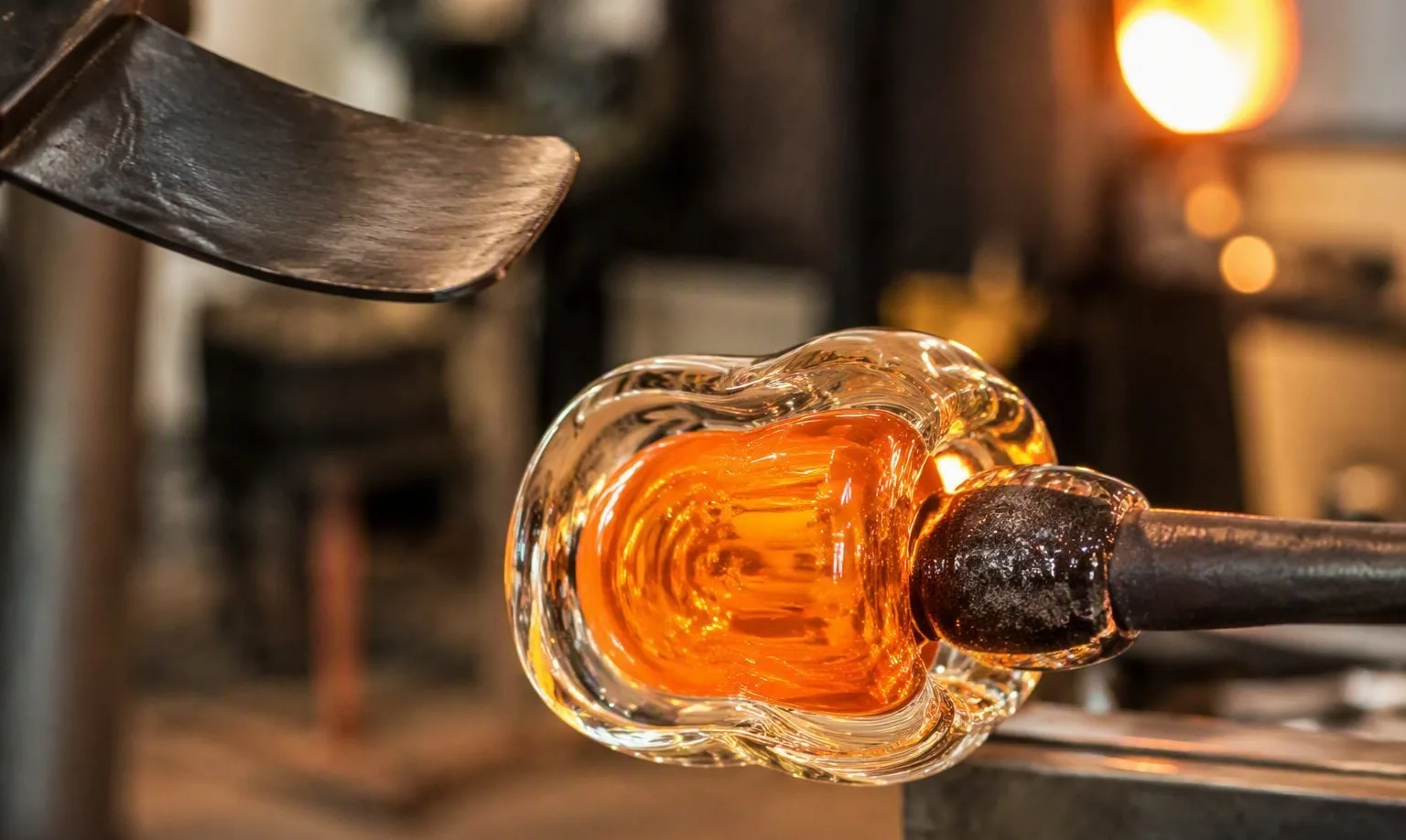 Artisan hand-blowing a cased glass tumbler